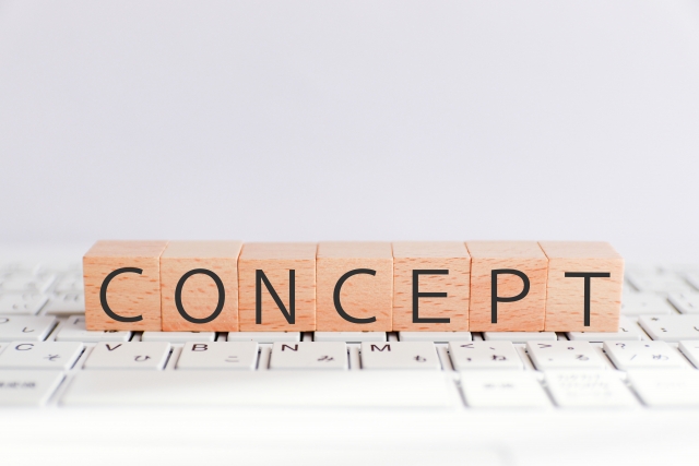 コンセプトと書かれた木のブロックが、パソコンのキーボードの上に置かれている。
