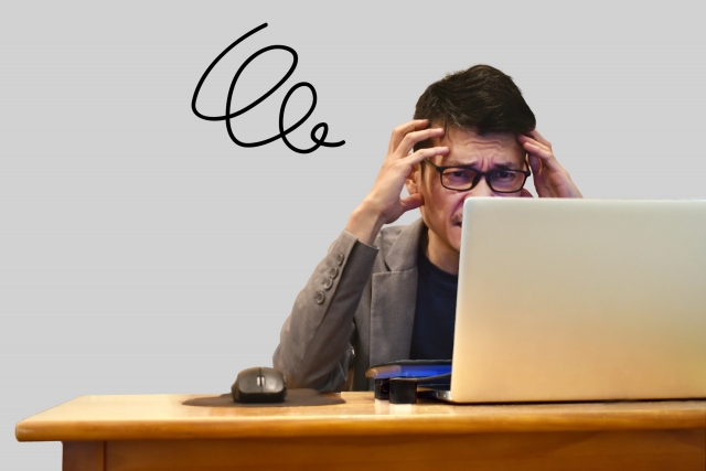 パソコンの前で頭を抱える男性